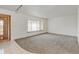 Bright living room with neutral carpet, a large window, and a decorative wood front door at 11310 W Center Ave, Lakewood, CO 80226