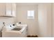 Bright laundry room with white washer and dryer, upper cabinets, and window at 17786 Olive St, Broomfield, CO 80023