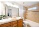 Bright bathroom featuring double sinks, granite counters, a soaking tub, and tiled shower walls at 124 3Rd St, Fort Lupton, CO 80621