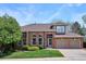 Charming two-story brick home featuring a well-manicured lawn, mature trees and an attached two-car garage at 9524 E Caley Cir, Englewood, CO 80111