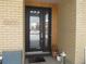 Close up of the front door featuring glass panels, brick siding, and modern design at 6850 E Archer Dr, Denver, CO 80230