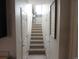 Well-lit hallway with carpeted stairs, multiple doors, and neutral paint at 6850 E Archer Dr, Denver, CO 80230