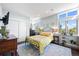 Bright bedroom with three windows, a metal bed frame, and a light blue rug on dark wood floors at 2826 Broadway St # 106, Boulder, CO 80304