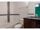 White bathroom featuring a tub with modern tile accents, vanity and dark wood cabinets at 8774 Martin Luther King Blvd, Denver, CO 80238
