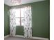 Bright bedroom features green accent walls, light gray carpet and a window with fern patterned curtains at 8774 Martin Luther King Blvd, Denver, CO 80238