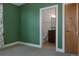 Bedroom with adjacent bathroom, accented by green walls and neutral carpet, next to a light wood door at 8774 Martin Luther King Blvd, Denver, CO 80238