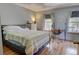 Bedroom with wood floors, black metal bed frame, two windows, and desk at 9771 W Cornell Pl, Lakewood, CO 80227