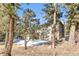 Back of house surrounded by trees and partially covered in snow at 30633 Kings Valley Dr, Conifer, CO 80433