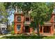 Red brick townhouse featuring arched doorway, mature trees, and manicured lawn at 1001 E 17Th Ave # 12, Denver, CO 80218