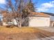 Tan house with attached garage and tree-lined yard at 19136 E Milan Cir, Aurora, CO 80013