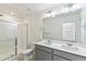 Bathroom featuring a double sink vanity, large mirror, toilet, and glass-enclosed shower at 21761 E 7Th Ave, Aurora, CO 80018