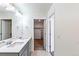 Bathroom featuring a double sink vanity, large mirror, and doorway leading to the walk-in closet at 21761 E 7Th Ave, Aurora, CO 80018