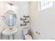 A stylish powder room features an oval mirror, pedestal sink, toilet, and wall-mounted shelves at 21761 E 7Th Ave, Aurora, CO 80018