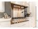 The stylish kitchen includes a stainless steel range, hood, and white cabinets at 10395 W 74Th Pl, Arvada, CO 80005