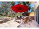 Charming outdoor patio featuring a stone fire pit, red umbrella, and mature trees at 10395 W 74Th Pl, Arvada, CO 80005