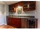 Elegant wet bar with granite counters, wood cabinets, and a beverage refrigerator at 10395 W 74Th Pl, Arvada, CO 80005