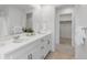 Bathroom with double sinks, white cabinetry, ample counter space, and a view into an adjacent walk-in closet at 13446 Amber Sky St, Parker, CO 80134