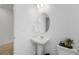 Stylish powder room with pedestal sink, oval mirror, and white walls at 13446 Amber Sky St, Parker, CO 80134
