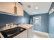 Laundry room with blue walls, white washer/dryer, and upper cabinets at 519 S Gaylord St, Denver, CO 80209