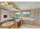 Bright bathroom with double vanities, a soaking tub under two windows with views, and a separate shower at 8403 Homestake Ct, Larkspur, CO 80118