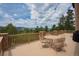 Outdoor patio featuring stone pillars, wood railings, and a table with four chairs, overlooking the tree tops at 8403 Homestake Ct, Larkspur, CO 80118