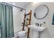 Stylish bathroom featuring a shower-tub combo, ladder shelf, and round mirror over a pedestal sink at 12193 W 51St Ave, Wheat Ridge, CO 80033