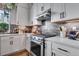 Modern kitchen with stainless steel appliances, white cabinets, and stylish tiled backsplash at 12193 W 51St Ave, Wheat Ridge, CO 80033