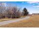 Paved walking path with split rail fence and mature trees, perfect for enjoying the outdoors at 12193 W 51St Ave, Wheat Ridge, CO 80033