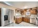 Well-lit kitchen with stainless steel refrigerator, tile floors, and wooden cabinets at 7005 S Ash Cir, Centennial, CO 80122