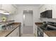 Galley kitchen featuring white cabinets, stainless appliances, and views to the living space at 7700 W Glasgow Pl # C, Littleton, CO 80128