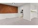 Bright living room featuring unique wood accent wall and neutral-toned carpet, leading into the kitchen at 7700 W Glasgow Pl # C, Littleton, CO 80128