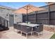 Covered patio area featuring an outdoor dining set, with a brick facade, and black fenced yard at 2945 E 26Th Avenue Pkwy, Denver, CO 80205