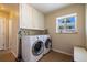 Functional laundry room with a side-by-side washer and dryer, upper cabinets, and a window at 428 W Valleyview Ave, Littleton, CO 80120