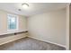 Finished basement room with carpet, window, and built-in shelving at 6150 S Fulton St, Englewood, CO 80111