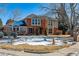 Brick two-story house with a landscaped yard and snow on the ground at 6150 S Fulton St, Englewood, CO 80111