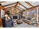 Living room with vaulted ceiling, exposed beams, and a stone fireplace at 6150 S Fulton St, Englewood, CO 80111