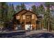 Exterior elevation displaying the home's architecture and garage entrance surrounded by lush trees and landscaping at 6752 S Columbine Rd, Evergreen, CO 80439