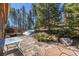 Charming stone patio with outdoor table and surrounding greenery at 6752 S Columbine Rd, Evergreen, CO 80439