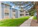 Two-story condo with stone accents, a balcony, well-maintained lawn and blue sky backdrop at 8600 E Alameda Ave # 22-208, Denver, CO 80247