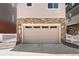 Exterior shot of an attached two-car garage with stone accents and a paved driveway at 12714 E Dickenson Ave, Aurora, CO 80014
