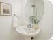 A modern bathroom features a pedestal sink, round mirror, and fresh decor at 2644 Devonshire Ct, Denver, CO 80229