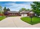 Inviting red brick home boasts a curved driveway leading to a two-car garage and lush green lawn at 3608 S Newport Way, Denver, CO 80237