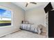 This bedroom features a ceiling fan, neutral decor, and natural light from a large window at 581 Park Blvd, Brighton, CO 80603