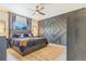 Stylish main bedroom featuring an accent wall, wood floors, ceiling fan, and a large window at 581 Park Blvd, Brighton, CO 80603