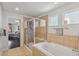 Tiled bathroom featuring a tub, separate shower with glass door, and view into main bedroom at 8865 E 28Th Ave, Denver, CO 80238