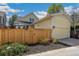View of a yellow two-story home with an attached garage and a wooden privacy fence at 8865 E 28Th Ave, Denver, CO 80238