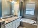 Elegant bathroom featuring a soaking tub, granite countertops, double sinks, and a large mirror with vanity lighting at 14673 E Belleview Dr, Aurora, CO 80015