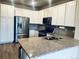 Bright kitchen with white cabinets, stainless steel appliances, and a granite countertop island with a sink and faucet at 14673 E Belleview Dr, Aurora, CO 80015