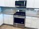 Modern kitchen equipped with stainless steel oven, cooktop, microwave, white cabinets, and granite countertops at 14673 E Belleview Dr, Aurora, CO 80015
