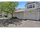 Exterior view showing garages with white doors and siding, adjacent to lush greenery and blue sky at 12625 E Pacific Cir # E, Aurora, CO 80014